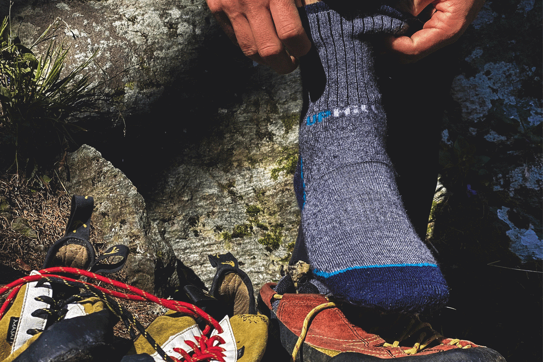 Person wearing blue hiking socks with climbing shoes and equipment on a rock