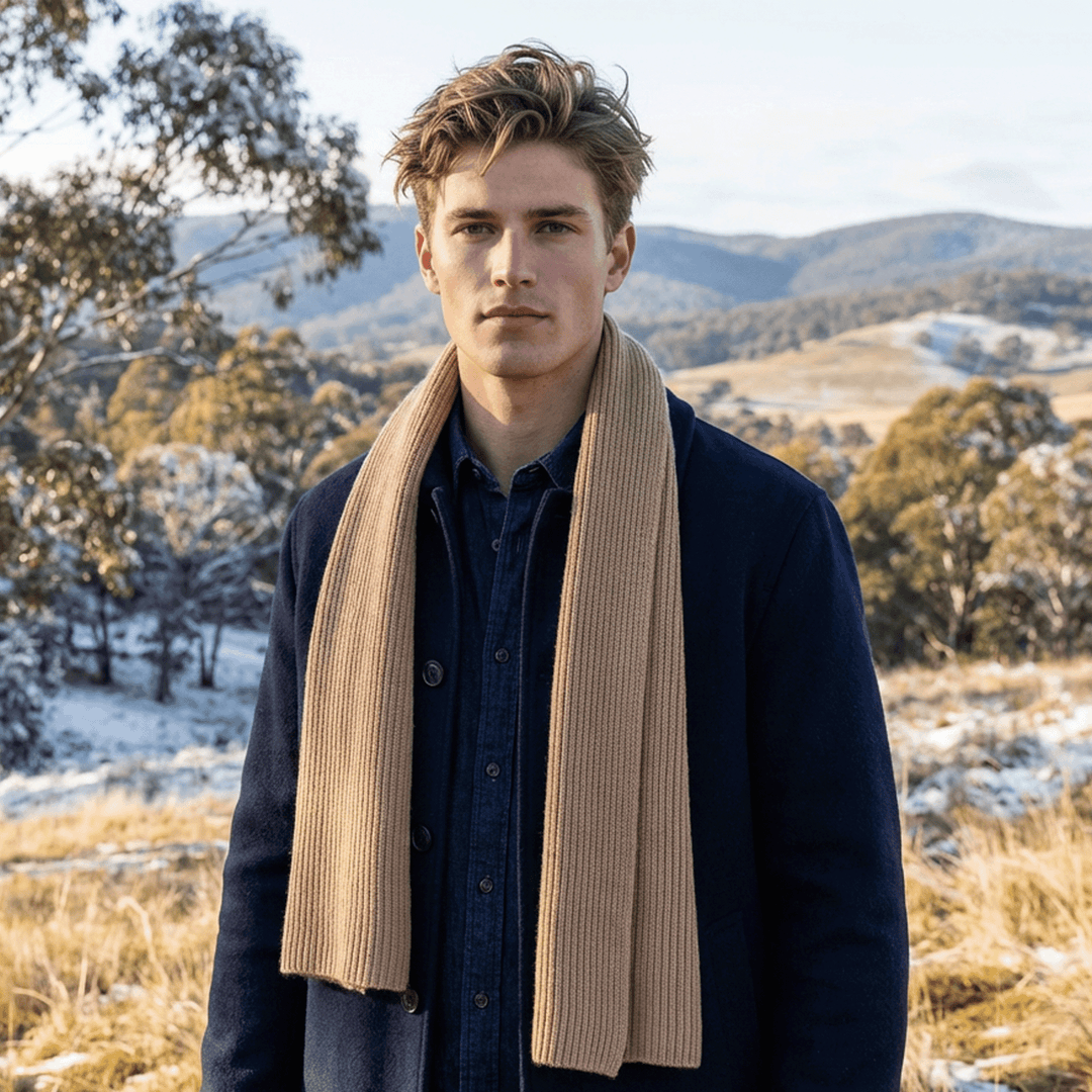 Man wearing a scarf in a snowy landscape with mountains