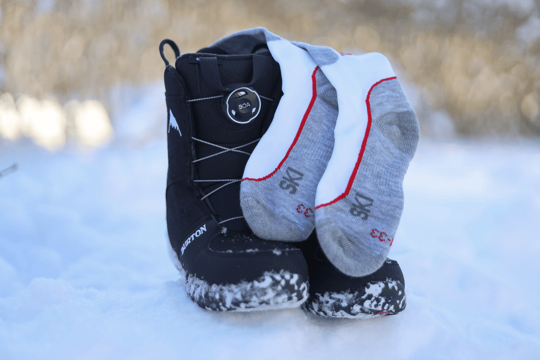 Black winter boots with gray socks on a snowy ground
