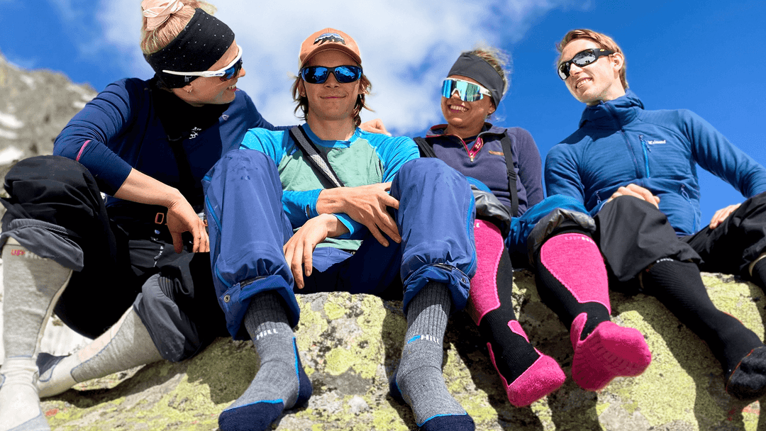 Four hikers sitting on a rock with mountainous background