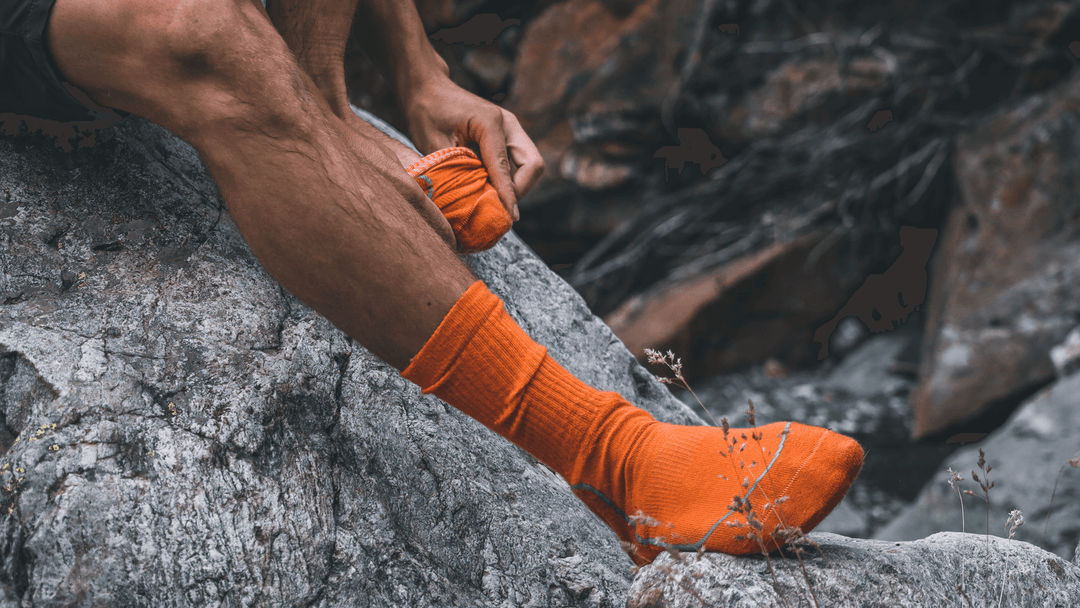 Person wearing orange socks on a rocky surface
